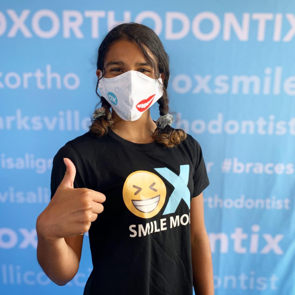OX Orthodontix patient with OX shirt and mask with thumbs up sign