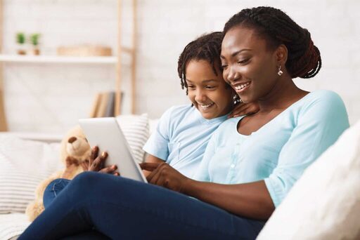 mother daughter viewing tablet on couch